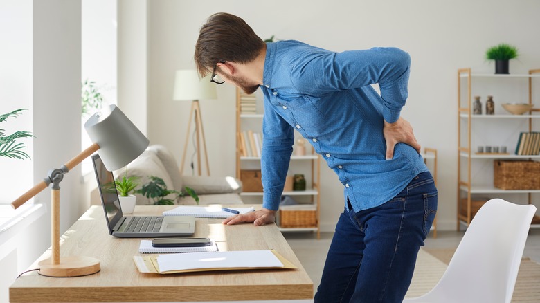 Man holding his back as he stands up from desk