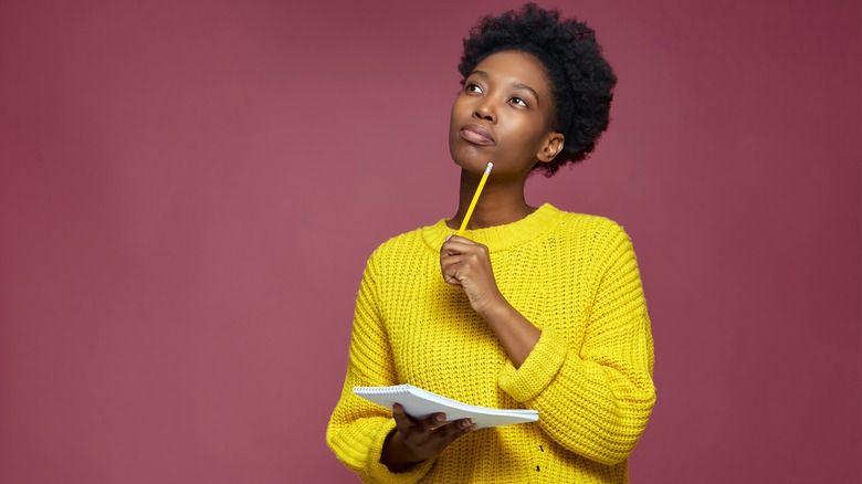 woman thinking with notepad and pencil