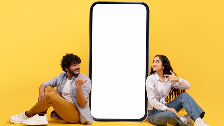 A man and woman sitting beside a phone