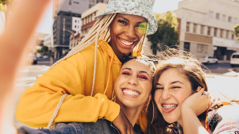 three smiling friends taking selfie