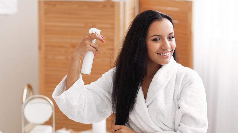 Woman spraying product on hair