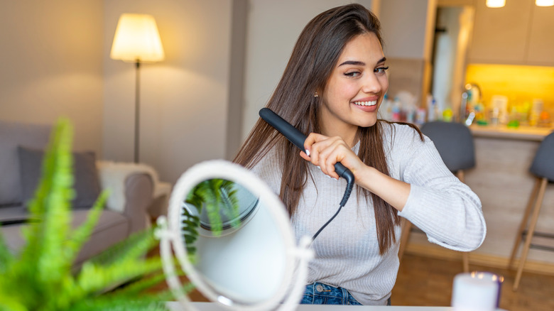 woman straightening hair at vanity