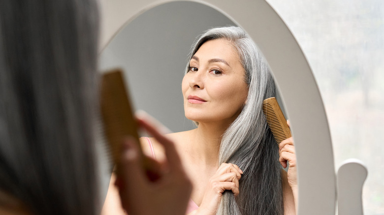 woman combing hair in mirror