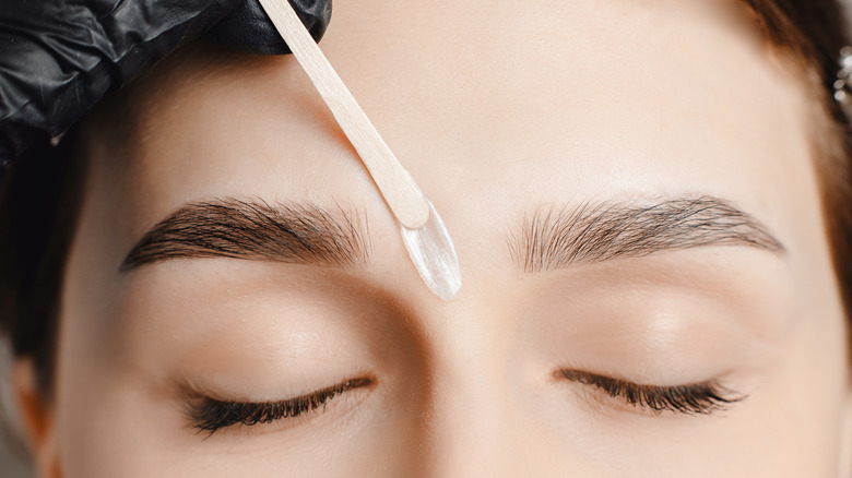 Woman waxing her eyebrows