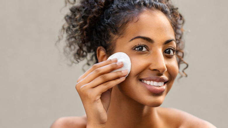 Woman using a makeup remover pad to take off her makeup