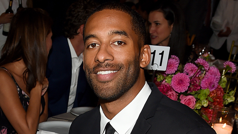 Matt James smiles with a black suit and tie