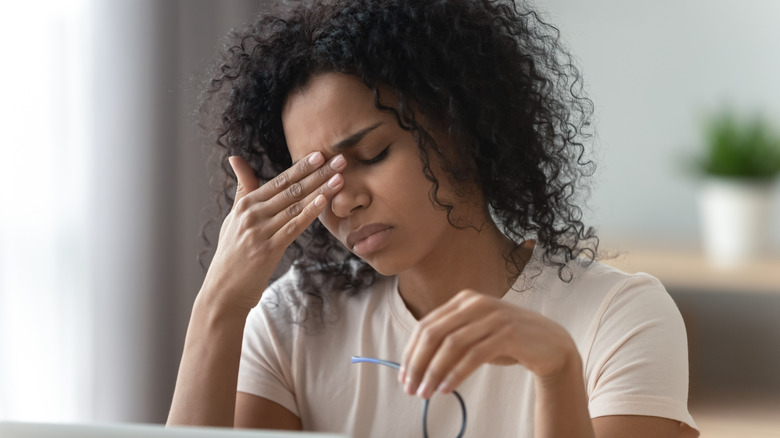 Woman holding head looking exhausted