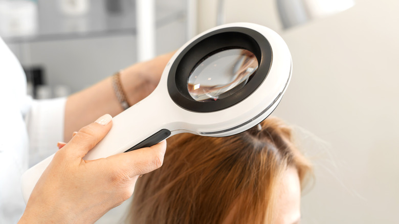 Doctor examining hair magnifying glass