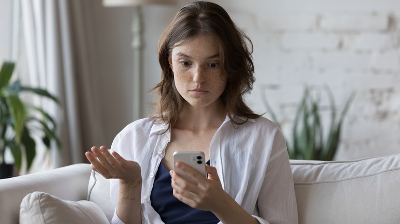 Woman looking at her phone unsure