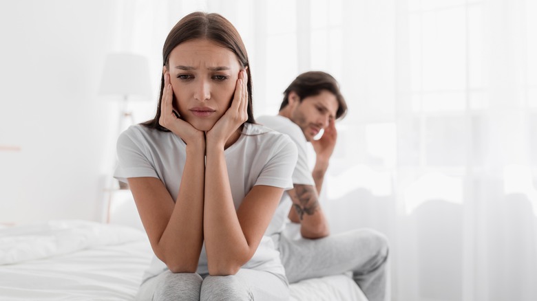 A couple fights in bed, woman looks frustrated