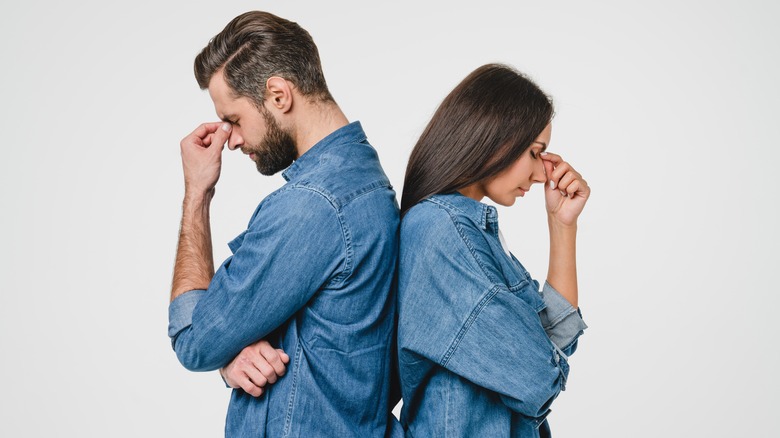 Couple stands back to back looking frustrated