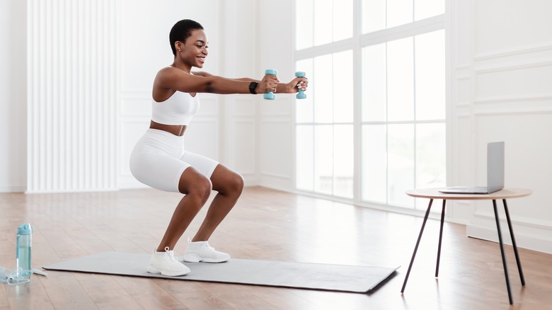 woman squatting with dumbells