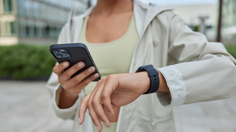 woman wearing smart watch checking phone