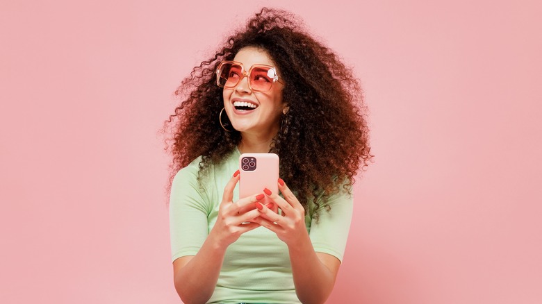 person holding phone pink background