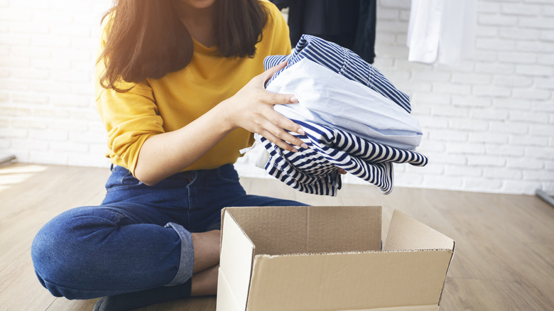 woman taking out clothes from box 