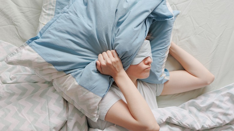 Woman covers her head with pillows