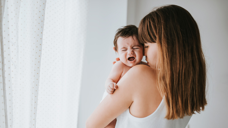 Crying baby in mother's arms