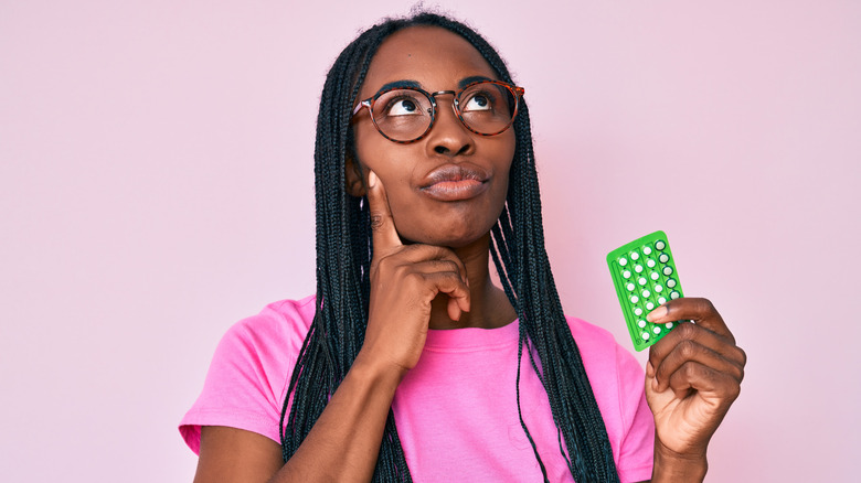 Black woman holding birth control pills