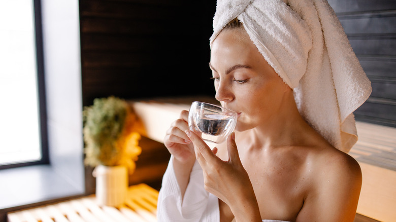 Woman drinking water in sauna