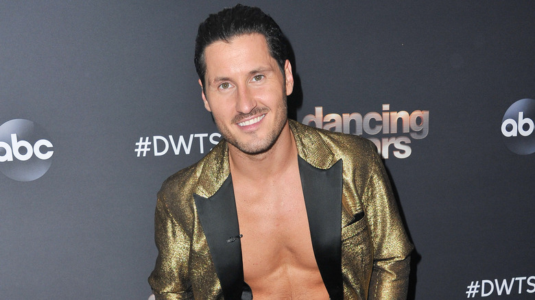 Val Chmerkovskiy smiling while wearing gold blazer