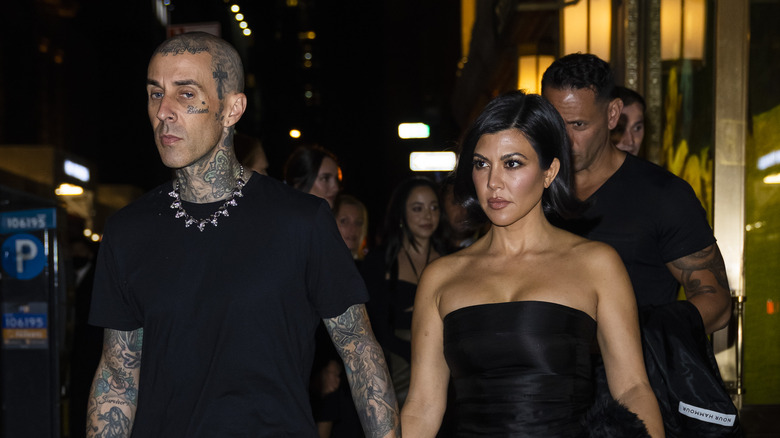 Kourtney Kardashian and Travis Barker hold hands. 