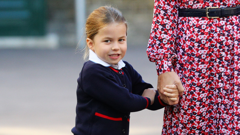 Princess Charlotte smiling and holding her mother's hand