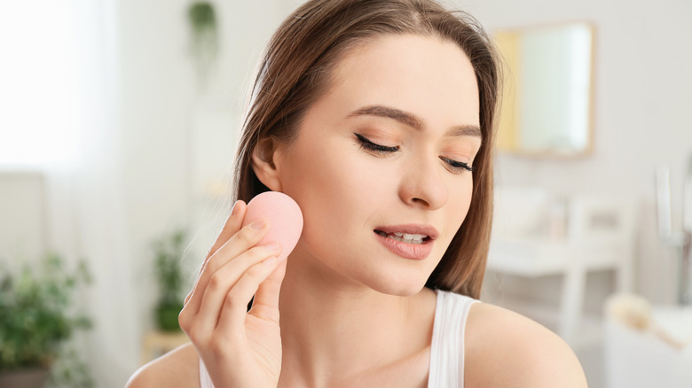 woman applying concealer with sponge