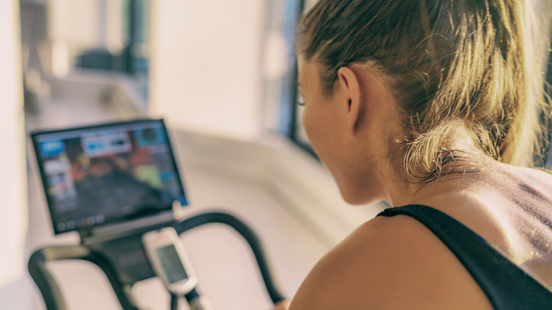 Woman riding a Peloton and looking at the screen