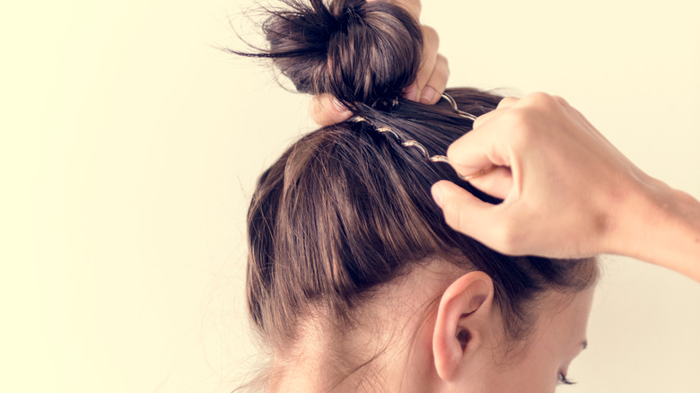 Person putting hair into bun