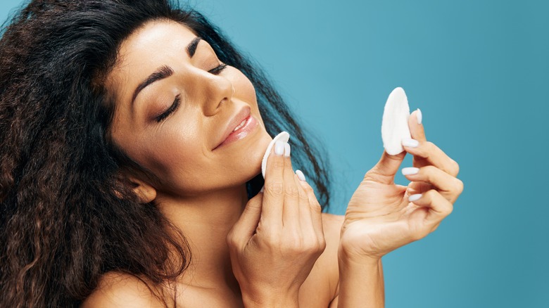 A woman using a makeup pad to apply toner