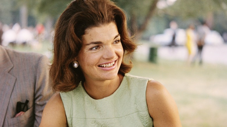 Jackie Onassis smiling in green dress