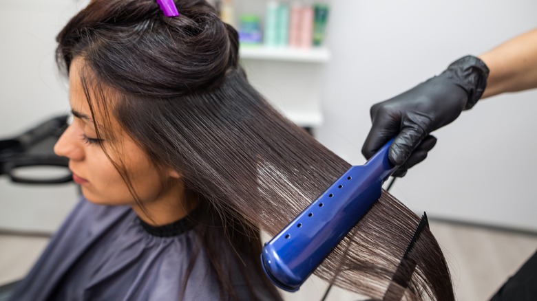 woman getting hair straightened at the salon