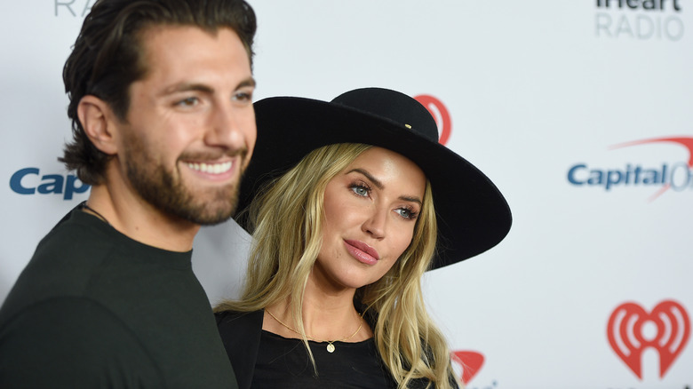 Jason Tartick smiling with Kaitlyn Bristowe on red carpet