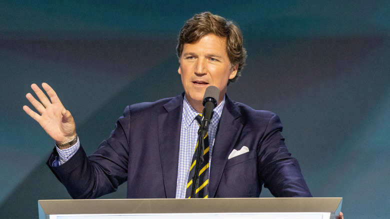 Tucker Carlson speaking at a podium