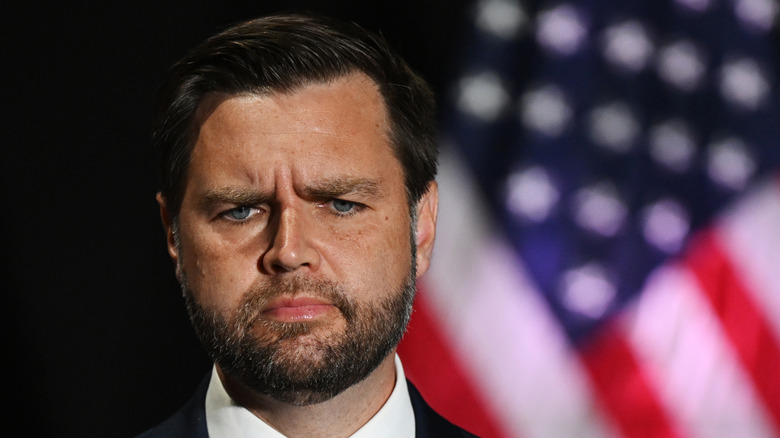 JD Vance frowning with US flag in background