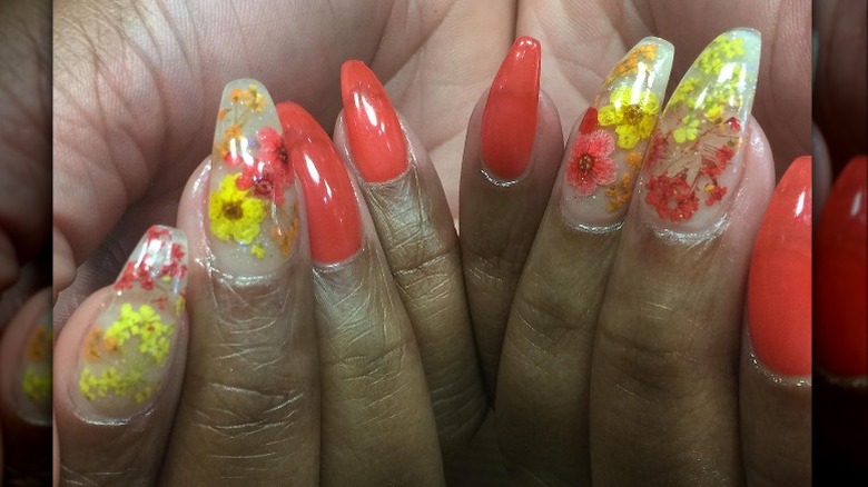 Hands showing off floral yellow and orange nail art