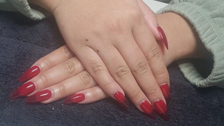 Hands with red nail polish resting on towel