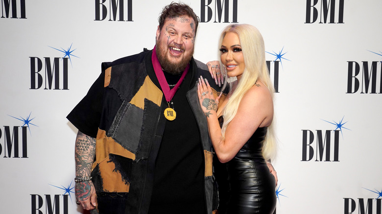 Jelly Roll and Bunnie Xo smiling on a red carpet