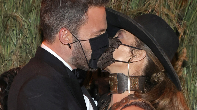 up close image of Jennifer Lopez and Ben Affleck kissing while wearing masks