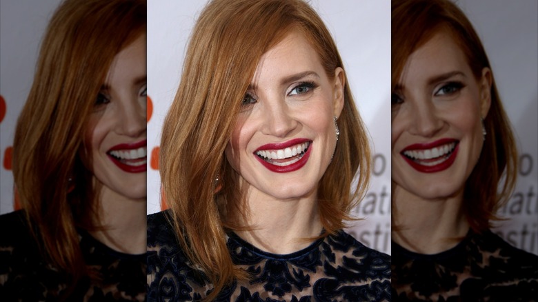 Jessica Chastain smiling for a picture while wearing red lipstick