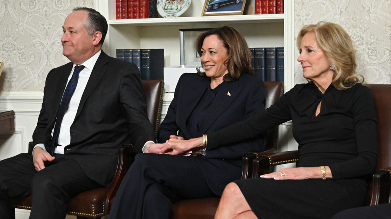 Jill Biden holding Doug Emhoff's hand with Kamala Harris in between them