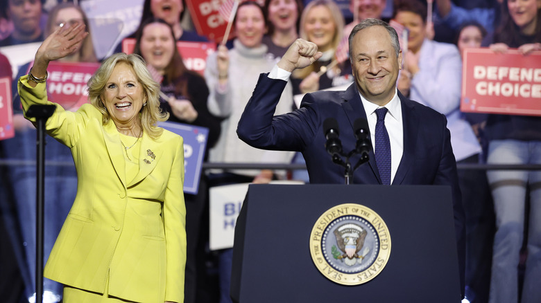 Jill Biden and Doug Emhoff holding up their hands onstage at an event