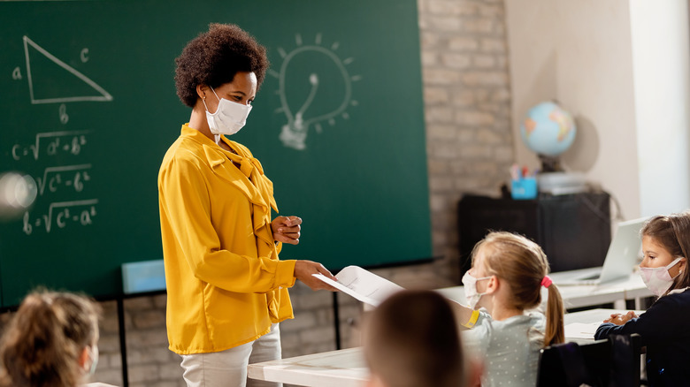 A masked teacher and masked children in a classroom 