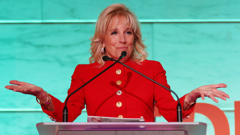 Jill Biden, wearing red, shrugs during a speech