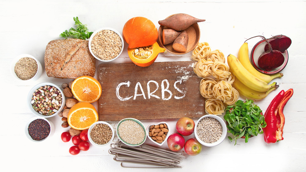 Variety of carbohydrates around board that says 'carbs'