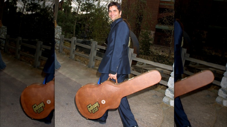 John Stamos carrying a guitar case