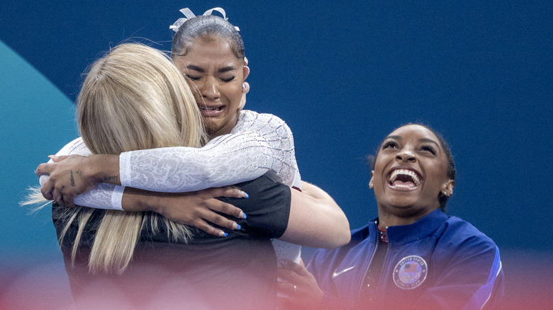 Jordan Chiles hugs her coach with Simone Biles watching on