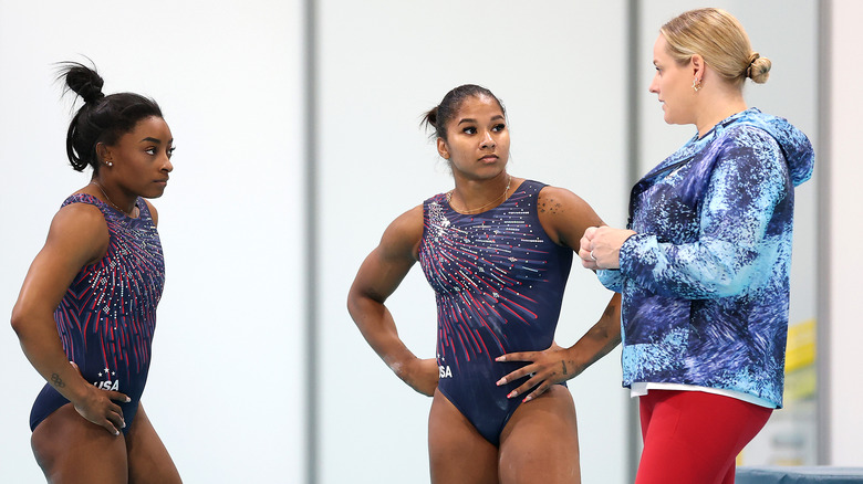 Simone Biles, Jordan Chiles, and Cecile Canqueteau-Landi talk in a gym