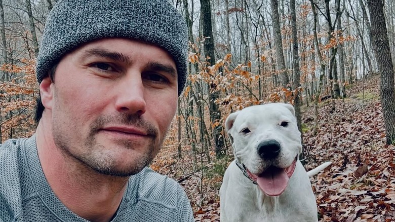 Josh Hall posing in the woods with a dog