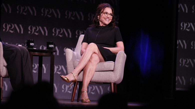 Julia Louis-Dreyfus sitting in a chair on stage